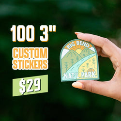 Promo graphic advertising 100 3-inch custom stickers for $29, featuring a hand holding a die cut vinyl decal illustrated with mountains, pine trees, a winding trail, and a rising sun labeled Big Bend Nat’l Park. Set against a dark green outdoor backdrop, highlighting durable, aesthetic waterproof adventure-themed stickers.