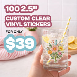 Advertisement showcasing a transparent clear vinyl sticker applied to a drinking glass. The floral design appears integrated with the glass surface, demonstrating the clear material effect. Large text promotes 100 custom 2.5-inch clear vinyl stickers for $39.