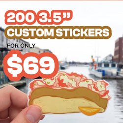 A hand holds a die-cut sticker featuring a lobster roll and a lemon slice, set against a blurred waterfront background with promotional text reading '200 3.5