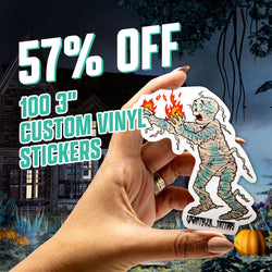 Image with text 57 percent off promo, 100 3 inch custom vinyl stickers, and 29 dollars. A hand holds a die cut custom sticker of a cartoon mummy with distressed bandages and flames emerging from its hands, drawn in a vintage horror comic style. Background shows a haunted house at night with pumpkins. Waterproof spooky aesthetic decal.
