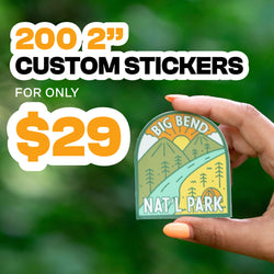 Promo image with bold text reading 200 2 inch custom stickers for only 29 dollars on a bright green background. A hand holds a die cut Big Bend Nat’l Park vinyl sticker featuring a retro-style landscape with green mountains, orange sunburst sky, pine trees, and a winding teal river. Vibrant outdoor aesthetic highlights waterproof custom vinyl stickers.