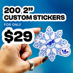 Hand holding a die-cut vinyl sticker shaped like a blue snowflake with a smiling face wearing sunglasses and a small Adidas-style trefoil icon printed in the corner. Bright blue gradient background with large text reading 200 2 inch custom stickers for $29. Popular keyword targets include winter stickers, snowflake decals, cool aesthetic stickers, and logo-style vinyl stickers.