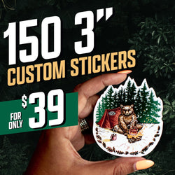 Hand holding a die cut sticker of a bear sitting beside a campfire with trees behind it and a red tent marked OGE. Dark forest background. On-image text 150 3 inch custom stickers and 39. Keywords: camping sticker, wilderness decal, outdoor adventure vinyl.