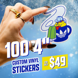 Promotional image for 100 four-inch custom vinyl stickers for 49 dollars, featuring a hand holding a die-cut cartoon sticker of a duck bundled in winter clothing sitting inside a blue mug with steam swirling upward. Text on the image reads 100 4 inch custom vinyl stickers for only 49 dollars. The background is icy blue with frosted winter branches.