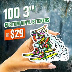 Image displaying text 100 3 inch custom vinyl stickers and 29 dollars. A hand holds a die cut custom vinyl sticker of a cartoon skiing bunny wearing goggles and bright neon winter gear, illustrated in a retro comic style with bold outlines and vibrant colors. Dynamic snow trail effect adds motion. Waterproof outdoor sports decal.