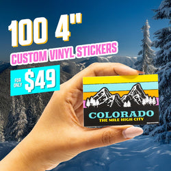 Hand holding a rectangular custom vinyl sticker featuring a bold Colorado The Mile High City design with black mountain silhouettes, white pine trees, and retro horizontal stripes in yellow, turquoise, orange, and pink. Snow-covered mountains and bright blue sky form the backdrop. On-image text reads 100 4