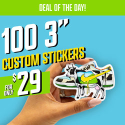 Promotional image with the header ‘Deal of the Day!’ Large text reads ‘100 3-inch custom stickers for only $29.’ A hand holds a die-cut sticker depicting a cow combined with a sneaker design: the cow’s body forms the shape of a shoe with a yellow swoosh-like graphic dripping down the side, green and blue color blocks, and black-and-white cow patterns. The background is solid light blue with bright green accent blocks behind the price