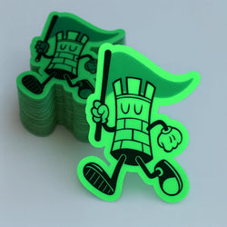 Stack of custom glow-in-the-dark die-cut stickers featuring a playful mascot character holding a flag. The specialty glow material shines brightly in low-light conditions, creating a vibrant green appearance that enhances the sticker’s outline and overall visibility. Shown alongside a stack of finished stickers, this image showcases the durability, precision cutting, and striking nighttime effect of glow-in-the-dark stickers for branding, giveaways, packaging, and promotional products.