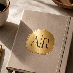 A round brushed gold metallic monogram sticker featuring the initials 
