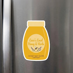 A die-cut refrigerator magnet shaped like a honey bottle displays the text 