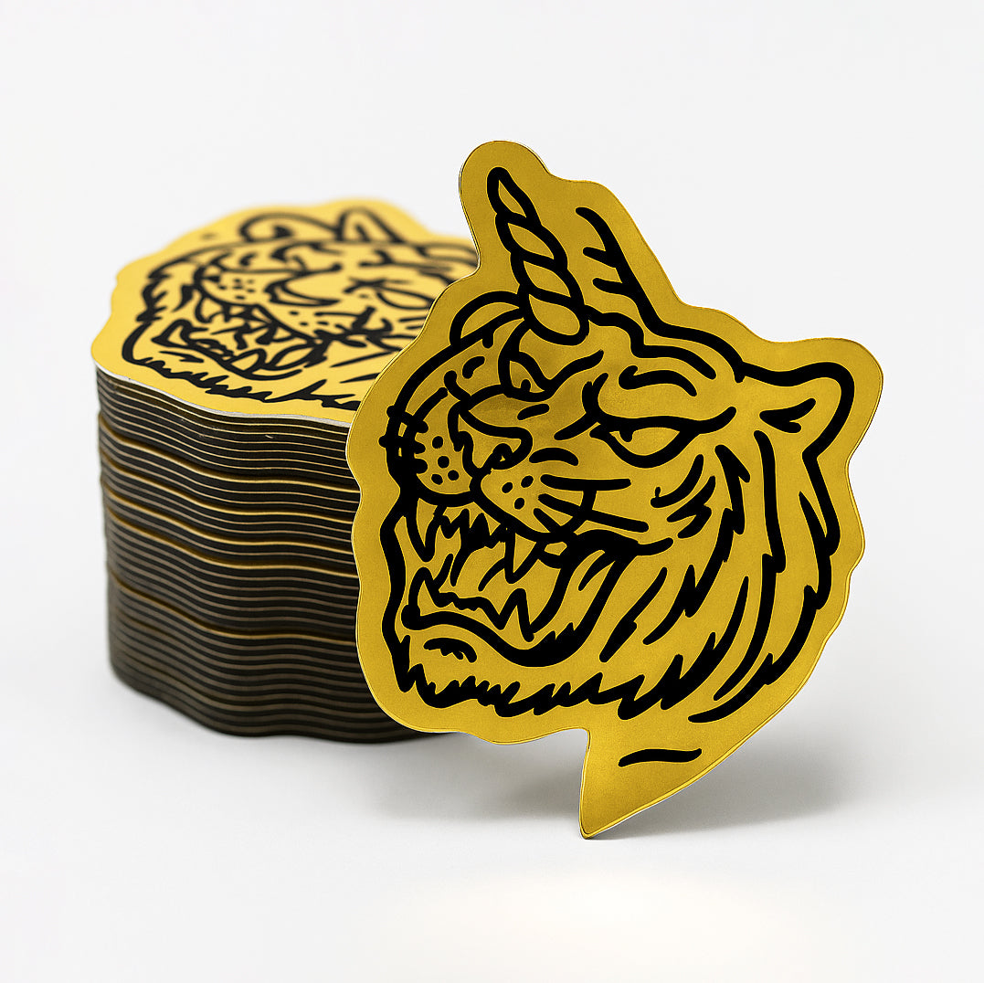 Stack of metallic gold and black tiger-themed stickers on a white background