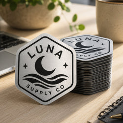 A brushed silver metallic hexagon sticker displays the logo 