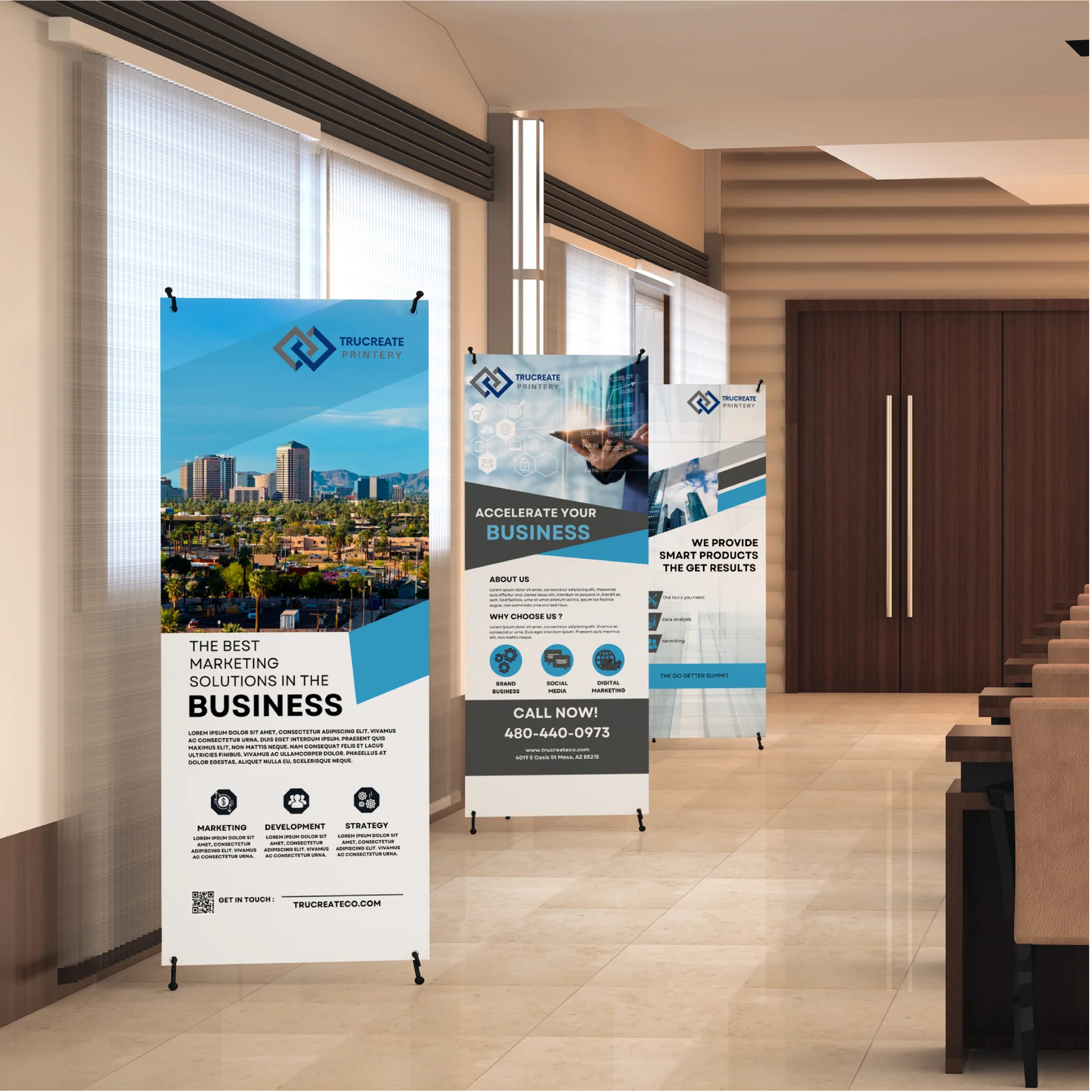 Three X-banner stands with custom printed vertical banners displayed in a modern office or conference lobby. The banners feature blue and white business marketing designs with city imagery, technology graphics, and text promoting marketing solutions, business growth, and services. Lightweight X-style stands with black feet hold the banners upright along a hallway with seating and wood-paneled doors in the background.