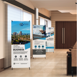 Three X-banner stands with custom printed vertical banners displayed in a modern office or conference lobby. The banners feature blue and white business marketing designs with city imagery, technology graphics, and text promoting marketing solutions, business growth, and services. Lightweight X-style stands with black feet hold the banners upright along a hallway with seating and wood-paneled doors in the background.