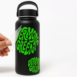Black water bottle with green die cut vinyl transfer sticker text 'VERMONT GREEN' held by a hand on a white background