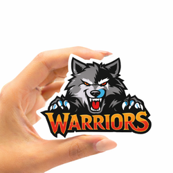 Hand holding a die-cut vinyl sticker featuring a gray and black wolf with red eyes, white teeth, blue tongue accents, and blue claws above the word Warriors in orange, yellow, and red lettering on a white background