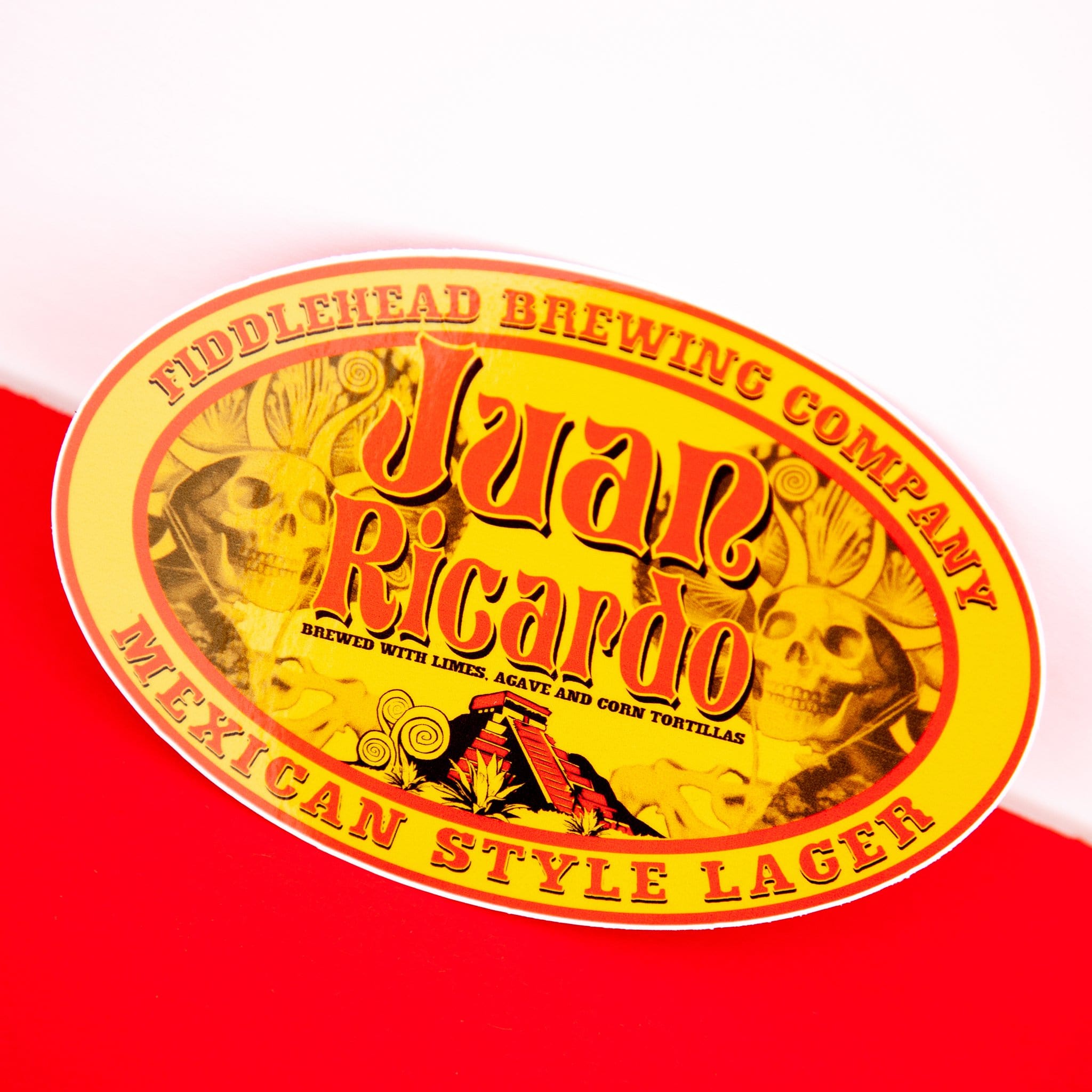 Yellow and red oval sticker with text fiddlehead brewing company Juan Ricardo Brewed with limes, agave and corn tortillas Mexican style lager