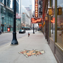 Custom shape Sidewalk decal mimics woman climging out of imaginary hole in sidewalk blond woman with red nails. Sticker is palced on sidewalk for artisttic purpose and place next to a restaurant in a city sidewalk environment.